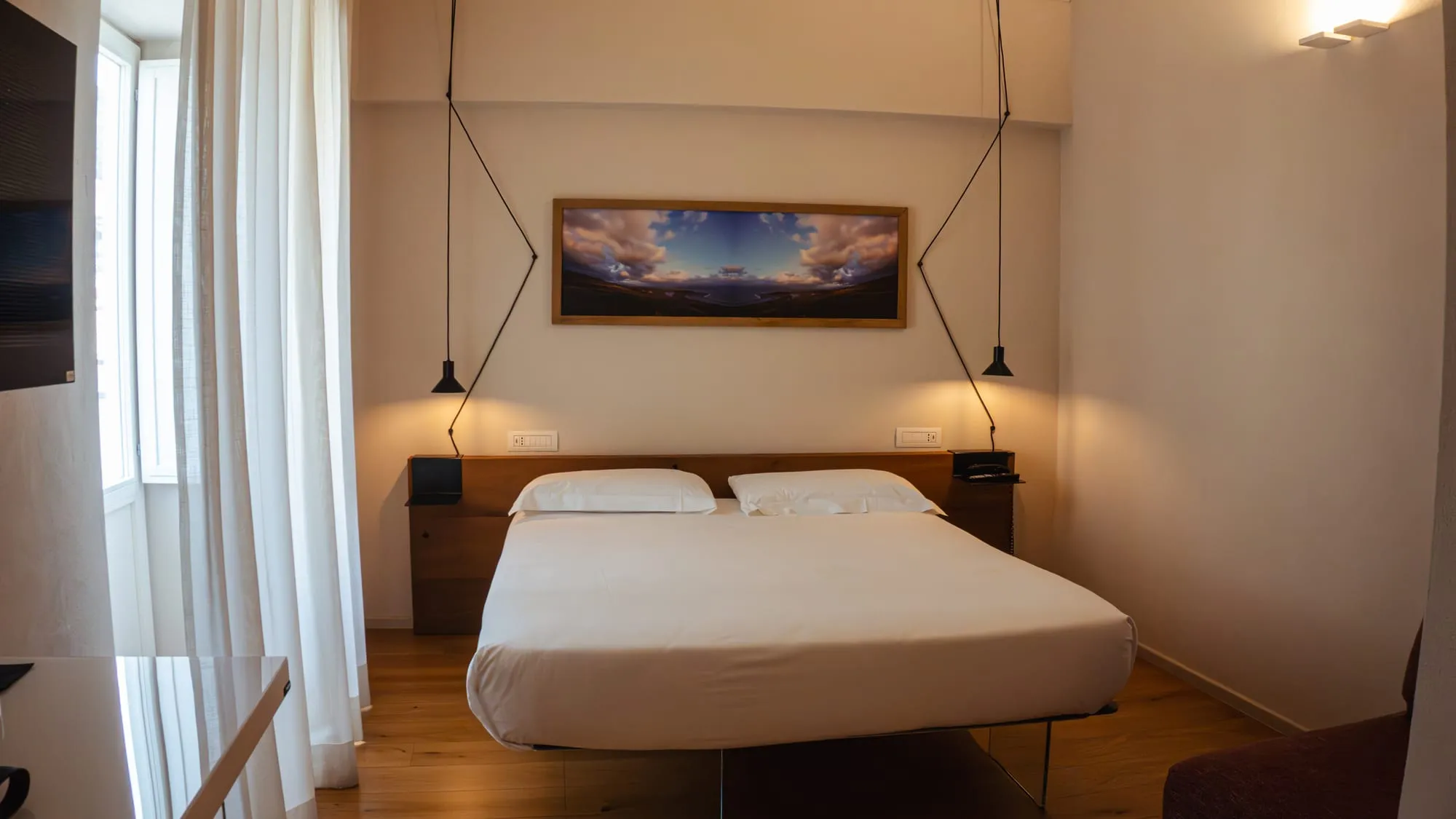 Una camera matrimoniale con un quadro e le luci sospese
