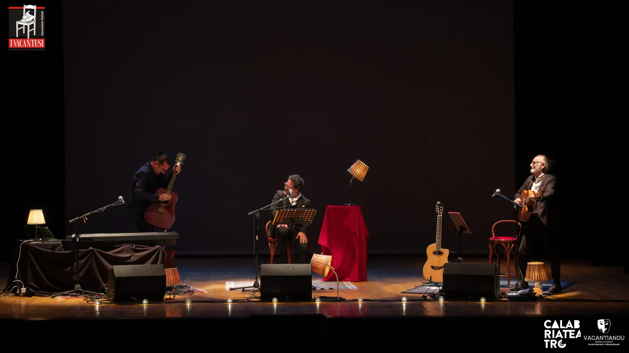 I tre interpreti in scena tra lampade, chitarre e un pianoforte