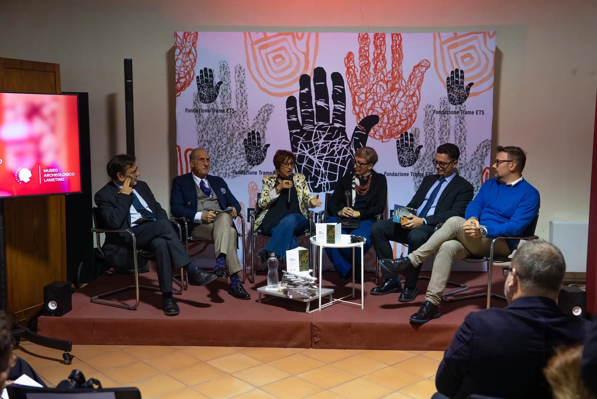 Presentazione su un palco con i relatori seduti in fila