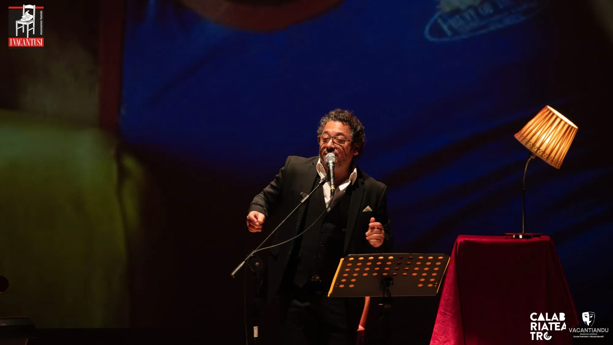 Un interprete canta al leggio sotto una luce calda