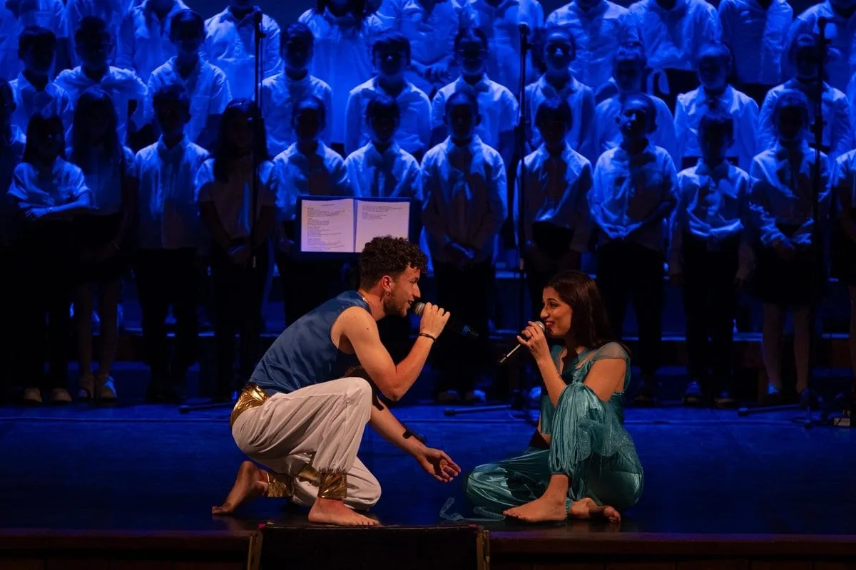 Due cantanti in scena davanti al coro